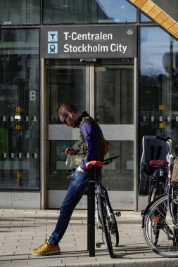 Stockholm, İsveç Genç bir adam şehir merkezinde T-Centralen de bisikletine yaslanır.