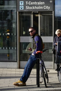 Stockholm, İsveç Genç bir adam şehir merkezinde T-Centralen de bisikletine yaslanır.