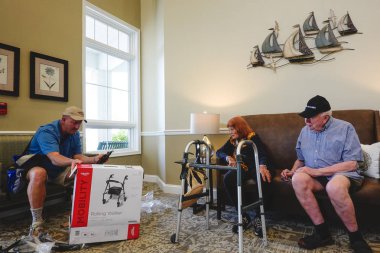 Solomons Adası, Maryland, ABD. Bir oğul, yaşlı ebeveynleri için bir huzurevinde yürüteç kuruyor..