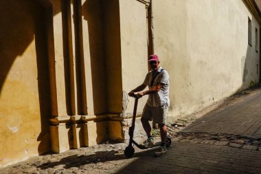Vilnius, Litvanya Bir adam Vilnius arka sokaklarında bir elektrikli mikro-mobilite scooter sürmek.