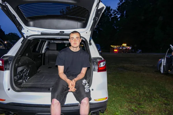 Amenia New York USA An 18 year old teenager sits on a tailgate at a  drive-in movie theatre.