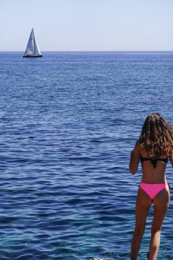 Syracuse, Sicilya, İtalya Genç bir kadın Ortygia adasında bir plajda denize bakar.