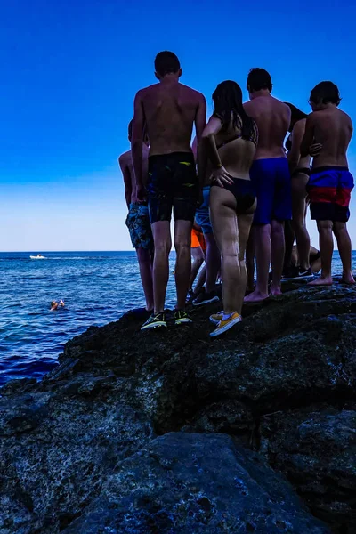 シラキュース シチリア イタリア ティーンエイジャーのグループは 水にジャンプする準備ができて岩の上に立っています — ストック写真