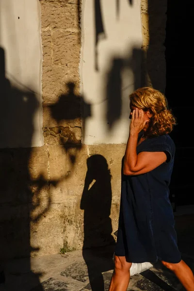 Syracuse, Sicily, Italy Pedestrians walk by the shadow of a street lamp in the late afternoon on Ortygia or Ortigia island.