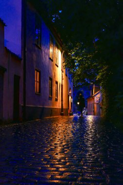 Visby, Gotland, İsveç Yağmurda ortaçağ kasabasının arnavut kaldırımlı sokaklarında yürüyen yalnız yayalar.