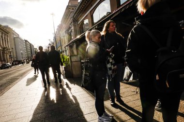 Eerikinkatu caddesindeki güçlü güneş ışığında Turku, Finlandiya yayaları.