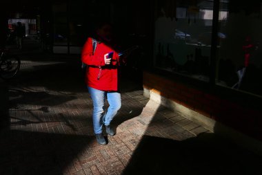 Turku, Finlandiya 'da bir kadın yüksek kontrastlı güneş ışığında ped bilgisayar taşır..