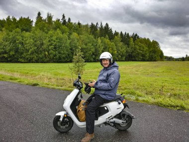 Картина, постер, плакат, фотообои "турку, финляндия мужчина, сидящий на электронном скутере на полях западной финляндии.", артикул 310605722