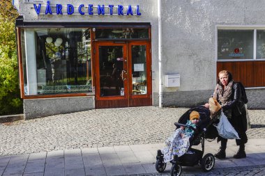 Stockholm, İsveç Bir kadın ve bebek arabası bir sağlık kliniğinin önünden geçiyor