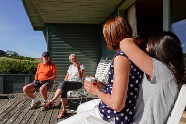 Hirtshals, Denmark A mother sits on her teenage daughter's lap on a sunny patio with grandparents.