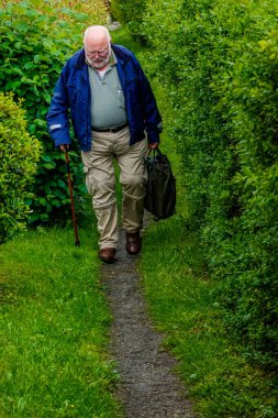 Ebeltoft, Danimarka Yaşlı bir adam çalılar arasında yeşil bir yolda yürüyor.