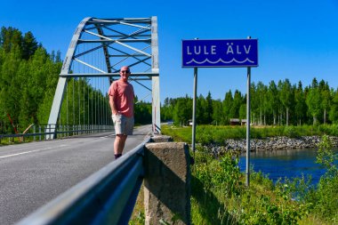 Jokkmokk, İsveç Güneşli bir günde Lule nehri ve köprüde duran bir adam.