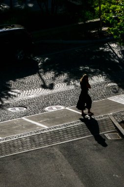 Stockholm, İsveç Güçlü gölgelerde tek başına kaldırımda yürüyen bir kadın..