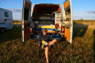 Resmo, Oland, İsveç Bir adam gün batımında karavanının önünde oturur