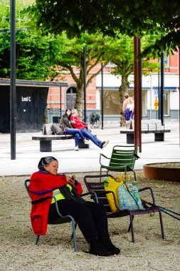 Lund, İsveç Merkez İstasyonu yakınlarındaki parkta bir kadın sandalyede oturuyor..