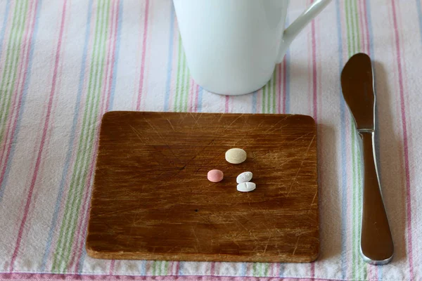 A place setting on a dinner table with medical pills.