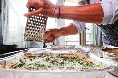 Bir kadın evde ıspanaklı domatesli kiş yapar ve parmesan peyniri rendeler..