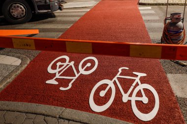 Stockholm, İsveç Liljeholmen 'de bir yol boyama ekibi şafak vakti bisiklet yoluna bir bisiklet sembolü çiziyor..
