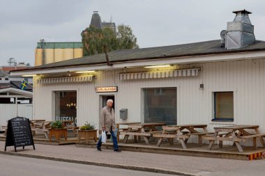 Enkoping, İsveçli yayalar şehir merkezinde küçük bir restoranın önünden geçiyorlar..