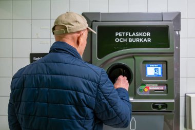 Stockholm, İsveç 'te bir adam para için konserve kutuları ve plastik şişe ve teneke kutular yazan İsveççe tabelalar alıyor..
