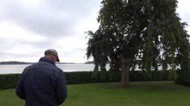 Stockholm, İsveç. Malaren Gölü kıyısında bir adam halka açık bir parkta yürüyor.. 