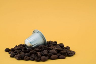 Kahve kapsülü, kahve çekirdekleri, sarı arka plan. Kapsül.