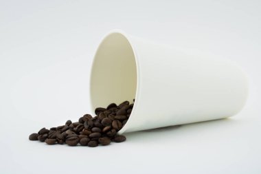 Dökülmüş kahve çekirdekleri, beyaz arka plan ile al-Out kahve bardağı. Kahve çekirdekleri.