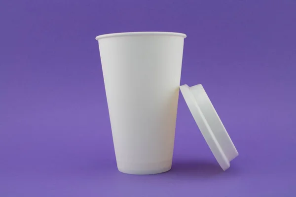 Papírový šálek kávy s víkem na boku, fialový podklad. — Stock fotografie