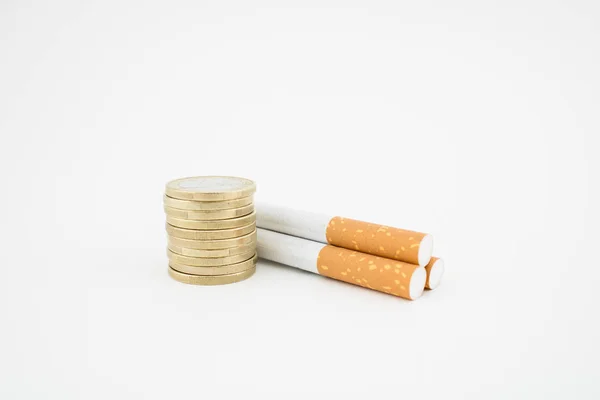 Cigarros y pila de monedas sobre fondo blanco. Concepto de impuestos y gastos . —  Fotos de Stock