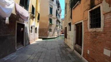 Venedik, İtalya-27 Temmuz 2018: 4K. İtalya 'nın Venedik şehrinde tipik bir caddede yürüyoruz. Sokağın sonunda bir kanal var. Yürüyen bir insanın öznel görüntüsü..