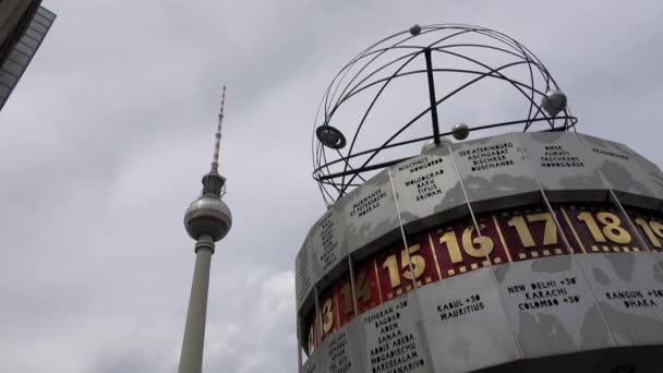 2018年7月9日 世界時計塔とテレビ塔は ドイツのベルリンの中心部に位置しています ヴェルツェイトゥールとベルリン フェルンゼヒューム 観光名所 曇ってる — ストック動画