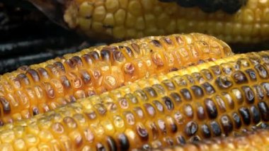 4 bin. Izgaradaki mısır koçanları. Aşçı onları hareket ettirir ve çevirir. Barbekü.