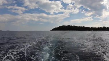 4 bin. Lokrum Adası feribottan uzaklaşıyor. Bir teknenin arkasından su yüzeyinde dalgalar. Adriyatik Denizi.