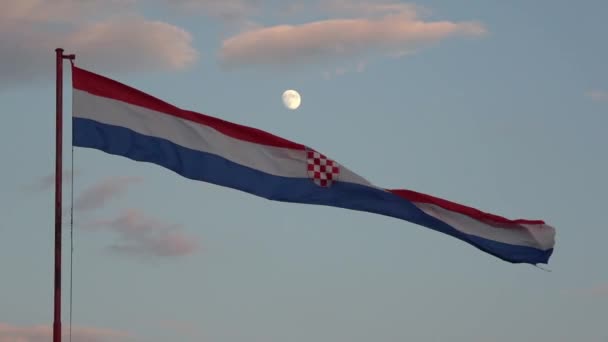 4K. Große kroatische Flagge weht im Wind. Es wird dunkel und der Mond ist herausgekommen. Die Flagge der Trikolore trägt in der Mitte das Wappen Kroatiens