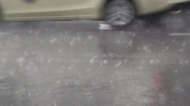 4 bin. Asfalta yağmur yağıyor. Sokakta şiddetli yağmur yağıyor. Araba trafiği. Arkada park etmiş arabalar var.