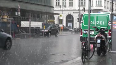 Berlin, Almanya-11 Temmuz 2018: 4K. Berlin 'de bir sokakta yağmur. Park etmiş bir polis arabası var, arabalar yağmurda hareket ediyor.