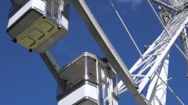 4 bin. Dönme dolap kulübeleri ya da dönen büyük tekerlekler. Eğlence parkı. Yolcu vagonları beyaz. Çark döner ve durur.