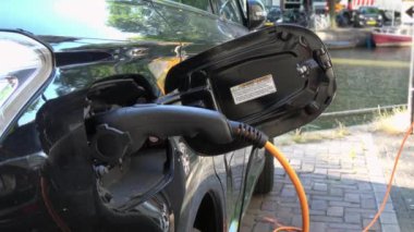 4 bin. Amsterdam, Hollanda 'da bir kanalın yakınına park etmiş elektrikli bir arabayı şarj etmek. Çevre dostu alternatif enerji. Kapat.