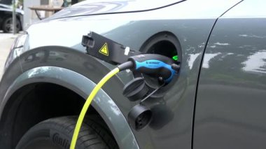 Amsterdam, Hollanda-06 Temmuz 2018: 4K. Şarj istasyonunda elektrik kablosu tıkanmış bir elektrikli araba. Çevre dostu alternatif enerji
