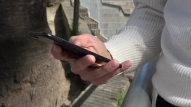 4 bin. Genç adam akıllı telefonunu kullanıyor. Telefonda yazı yazan, internette gezen ve sosyal ağları kontrol eden ellerin yakın çekimi