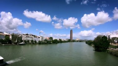4 bin. İspanya 'nın Sevilla şehrinin zamanı. Guadalquivir nehrinin üzerinde güzel bulutlar. Ufukta Sevilla Kulesi veya Pelli Kulesi var.