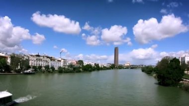 Torre Pelli ya da Torre Sevilla 'nın zamanı. Sevilla, İspanya' da ünlü bir gökdelen. Gualdalquivir nehri boyunca giden tekneler var. Güzel bulutlar. Yakınlaştır