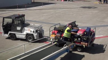 Bari, İtalya-25 Mayıs 2018: 4K. Teknik bir personel ticari havayolu uçağına konveyörden bagaj yüklüyor. Taşıyıcı bant uçağının bagajı. Gidiş terminali