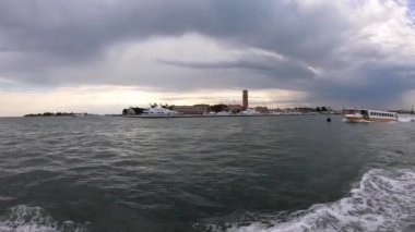 Venedik, İtalya-26 Temmuz 2018: 4K. Su otobüsü ya da İtalya, Venedik 'te bir liman yakınında giden toplu taşıma gemisi. Venedik gölünde yelken açan bir teknenin manzarası..