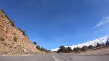 , İspanya-16 Nisan 2018: 4K. Zaman atlaması, bir arabayı dağ yolunda sürmek, etrafındaki dağlarda kar var. Sierra Nevada 'da güneşli bir gün, İspanya-Adrian.