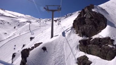Sierra Nevada, İspanya-17 Nisan 2018: 4K. Kayak merkezindeki karlı bir dağa çıkan teleferik ya da teleferik görüntüsü. Dağda kayalar var. Sierra Nevada, İspanya-Adrian.