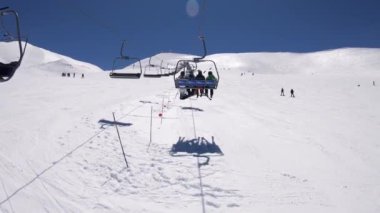 Sierra Nevada, İspanya-17 Nisan 2018: 4K. Kayak merkezindeki karlı bir dağa çıkan bir asansörde dört kişi oturuyor. Kayak yapan insanlar var. Sierra Nevada, İspanya-Adrian.