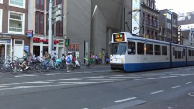 Amsterdam, Hollanda-05 Temmuz 2018: 4K. Amsterdam, Hollanda 'nın ana caddesinden tramvay geçiyor. Turistler caddeyi geçerken arabaları ve tramvayı geçiyor.