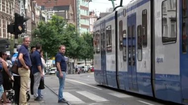 Amsterdam, Hollanda-06 Temmuz 2018: 4K. Amsterdam, Hollanda 'da tramvay karşıdan karşıya geçiyor. İnsanlar yaya geçidini geçiyor.