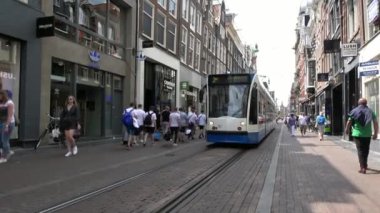 Amsterdam, Hollanda-06 Temmuz 2018: 4K. Amsterdam, Hollanda 'nın ticari caddesinden geçen bir tramvay. Turistler caddelerde yürürler.